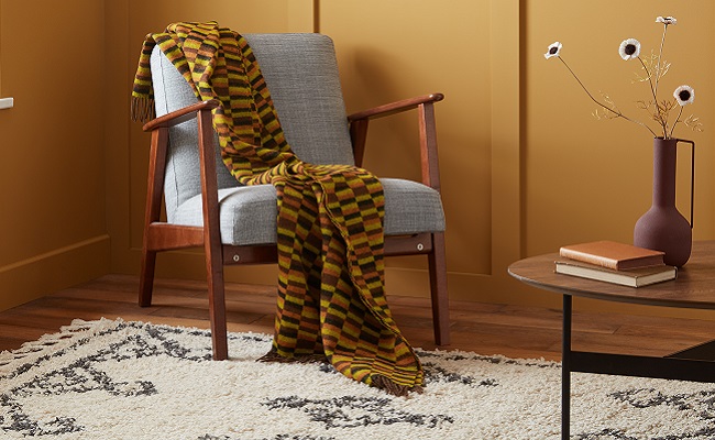 District line throw draped over neutral wooden chair against yellow wall